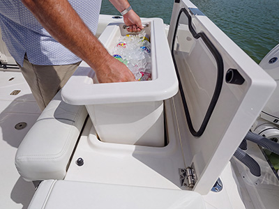 Person lifting the removable insulated cooler from the aft cockpit storage compartment on the Pursuit S 288 center console.