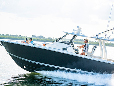 A woman at the helm of Pursuit Boats S 358 Sport Center Console boat running.