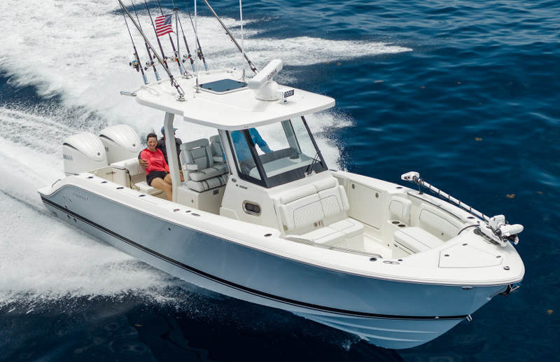 Pursuit center console boat running with three people aboard and fishing rods mounted upright on the hardtop.