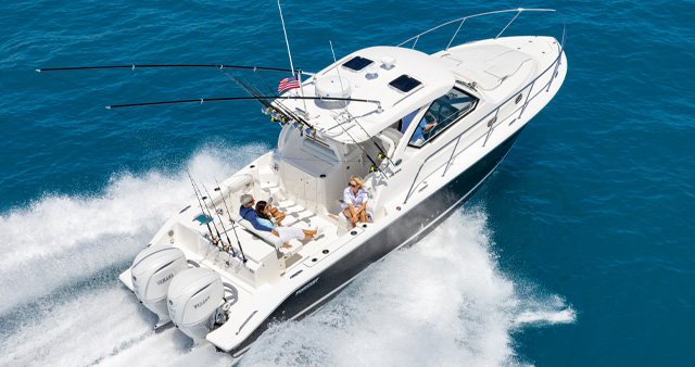 Aerial profile view of white OS 355 offshore boat with liveaboard space and twin Yamaha outboard engines running right.