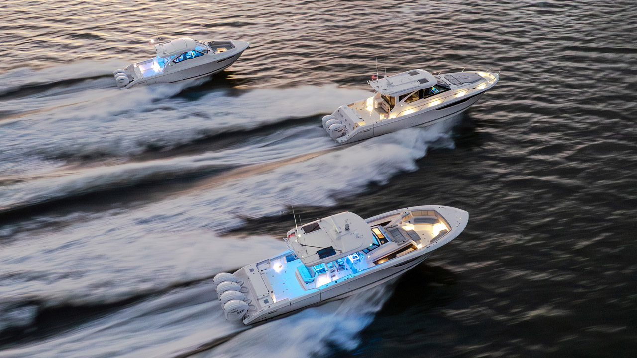 Pursuit Boats fleet of flagship models lit up and running at dusk.