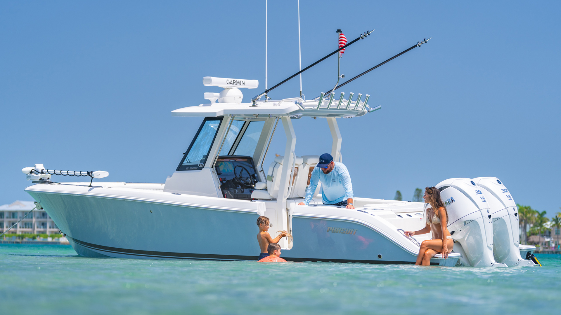 Pursuit S 288 center console boat anchored in shallow coastal waters with a family swimming and relaxing alongside the boat.