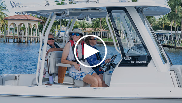 A group of three happy women ride aboard a Pursuit S 288 Sport Center Console, with one confidently driving the boat.