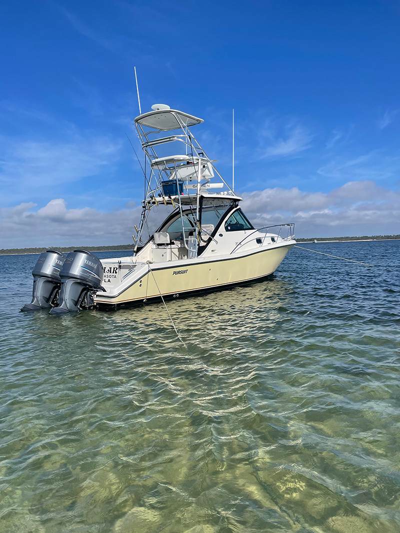 A yellow Pursuit Boat with tower in clear shimmering waters.