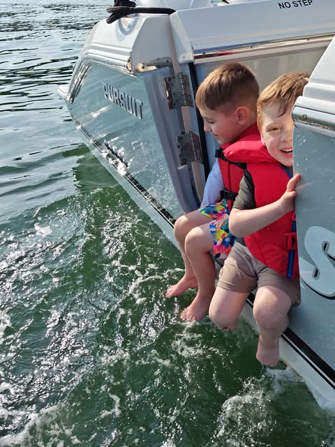 Two boys sit by the side door of the Pursuit S 368 Sport.