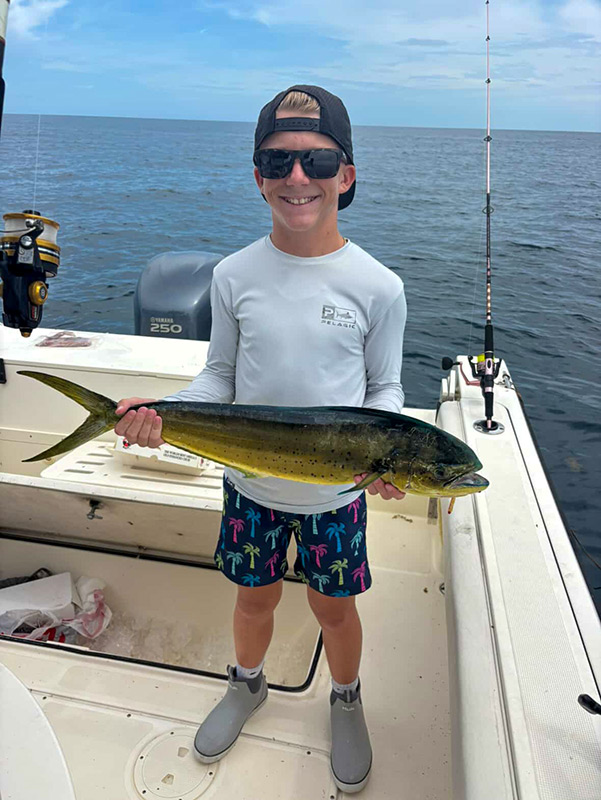 A boy proudly holds a fish aboard the Pursuit 2870 Center Console.